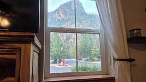 Ein Fenster mit Blick auf einen Berg und Bäume.