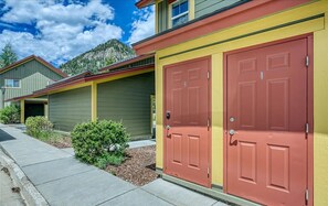 A row of two-story buildings with red doors, a green exterior, and a mountain backdrop. - The Royal Shreddar - Remote Work Ready (Frisco)