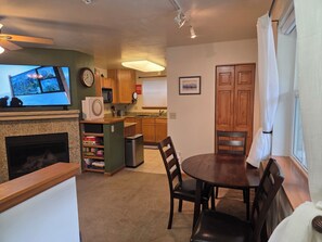 A cozy living room with a fireplace, a television, and a dining area with chairs and a table. - The Royal Shreddar - Remote Work Ready (Frisco)