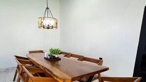 A dining area with a wooden table and chairs, a hanging light fixture, and a potted plant. - La Casona Suchitoto  (Suchitoto)