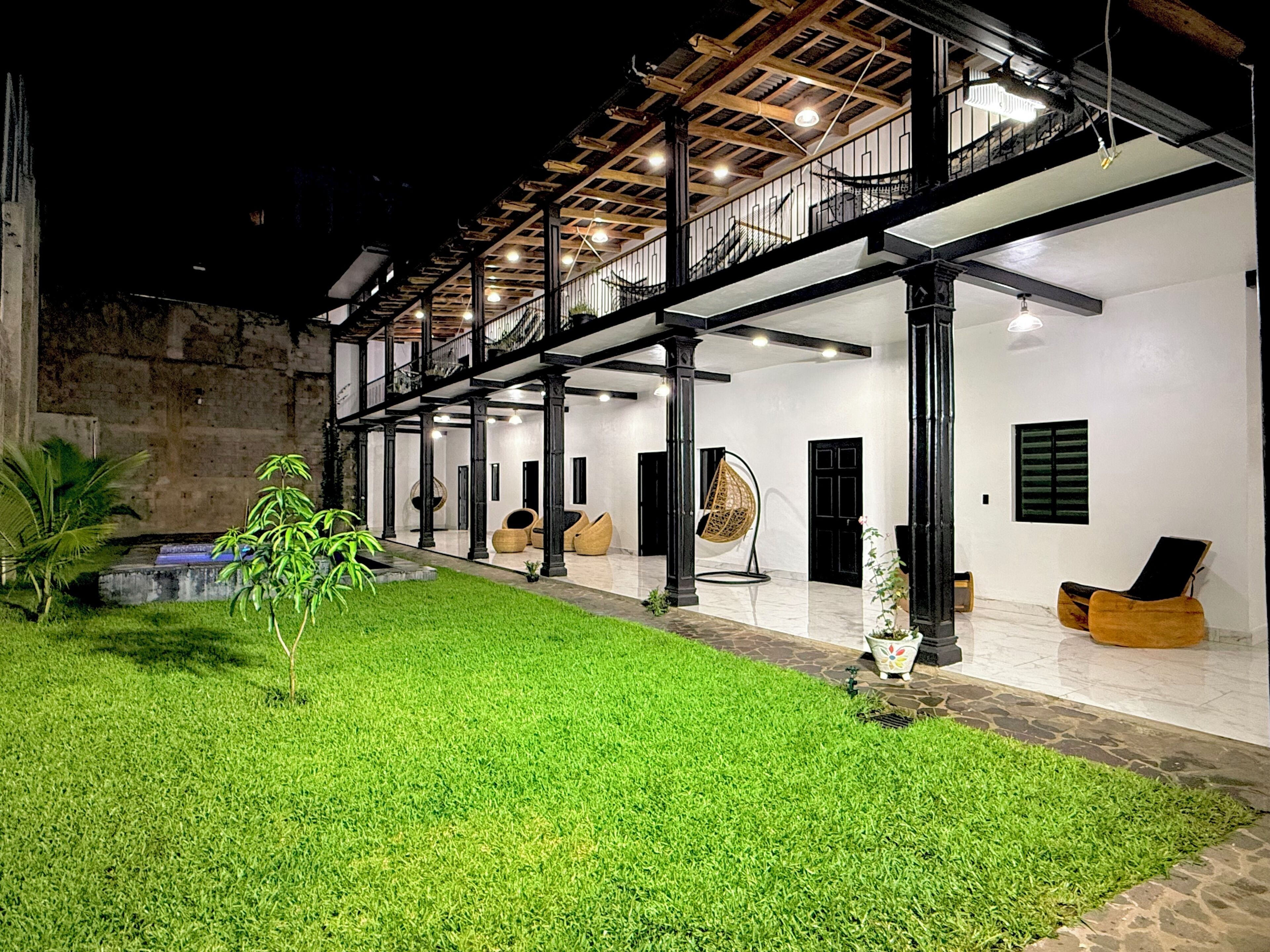 A spacious outdoor area with a well-maintained lawn, seating arrangements, and a staircase leading to an upper level.