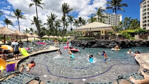 A water park with a pool, lounge chairs, and palm trees.
