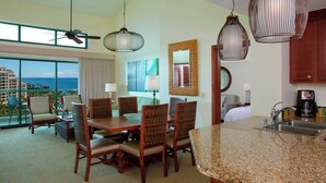 A hotel room with a dining area, kitchen, and a large window with a view.