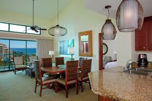 A hotel room with a dining area, kitchen, and a large window with a view.