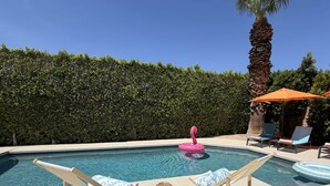Ein Swimmingpool mit Liegestühlen und einem Flamingo-Schwimmpunkt.