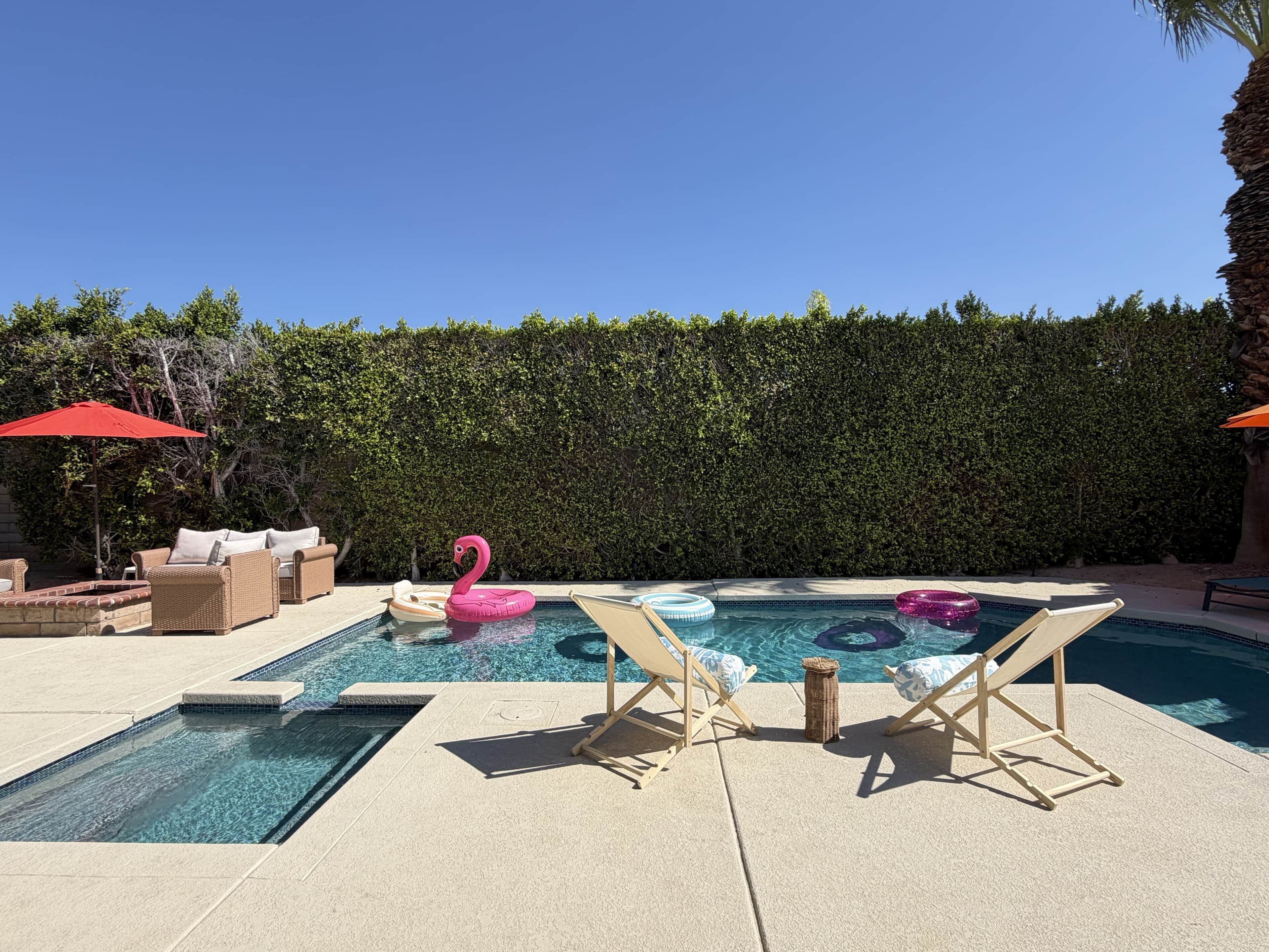 A swimming pool with lounge chairs and a flamingo float.
