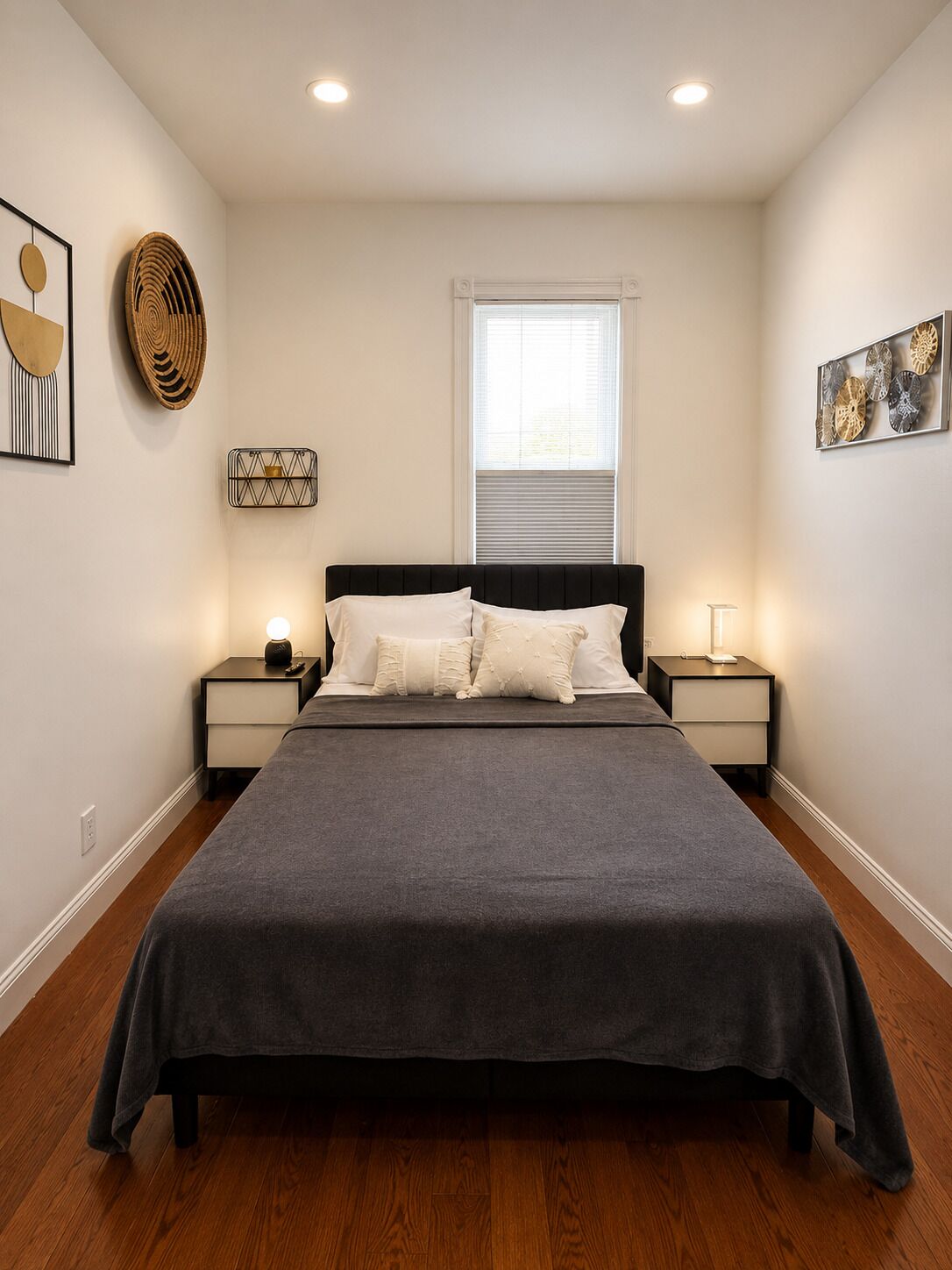 A bedroom with a bed, two bedside tables, a window, and wall decorations.