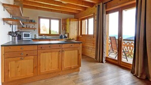 L’intérieur d’un chalet en bois comprend une cuisine, un coin repas et un balcon avec vue.
