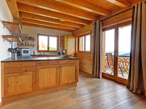 A wooden cabin interior with a kitchen, dining area, and a balcony with a view. - Perle des Collons by Interhome (Thyon-Les Collons)