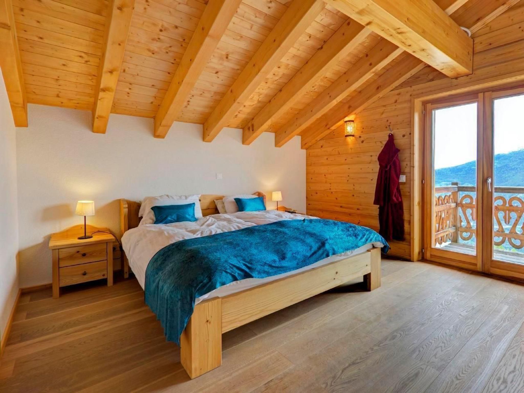 A wooden bedroom with a bed, nightstands, and a balcony with a railing.