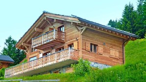 Un chalet en bois doté d’un balcon, situé sur une colline.