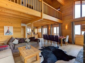 A spacious wooden interior with a dining area, a sofa, and a ceiling with a balcony. - Perle des Collons by Interhome (Thyon-Les Collons)