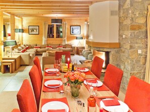 A dining area with a long table set for four, a fireplace, and a stone wall. - Teychenne Mungo by Interhome (Thyon-Les Collons)