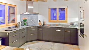 A modern kitchen with dark cabinets, a marble countertop, and a window above the sink. - Teychenne Mungo by Interhome (Thyon-Les Collons)