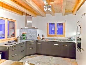 A modern kitchen with dark cabinets, a marble countertop, and a window above the sink. - Teychenne Mungo by Interhome (Thyon-Les Collons)