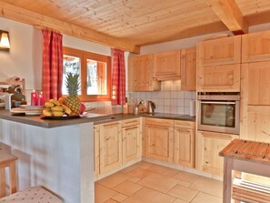 Eine Küche mit Holzausstattung, einer zentralen Kochinsel und einem Fenster mit Vorhängen.