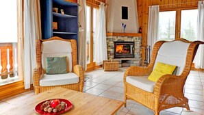 Ein gemütliches Zimmer mit Korbmöbeln, einem Kamin und Holzvertäfelung.