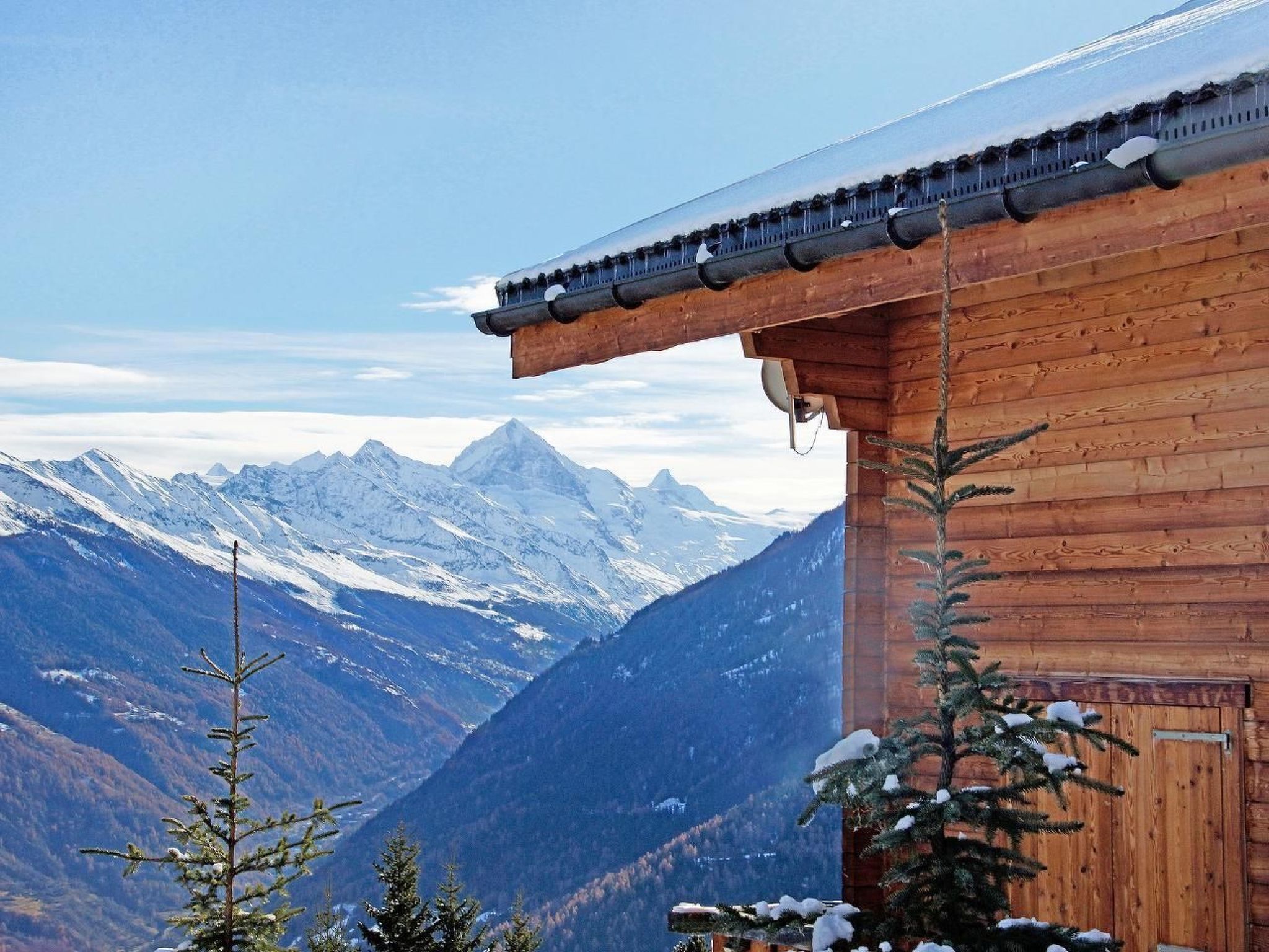 Eine Holzhütte mit Blick auf schneebedeckte Berge.