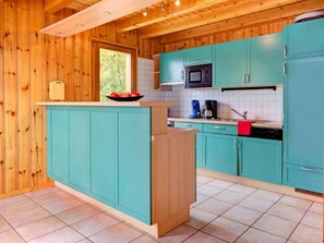 A kitchen with teal cabinets, a wooden island, and a window. - Chalet Krokus by Interhome (Thyon-Les Collons)