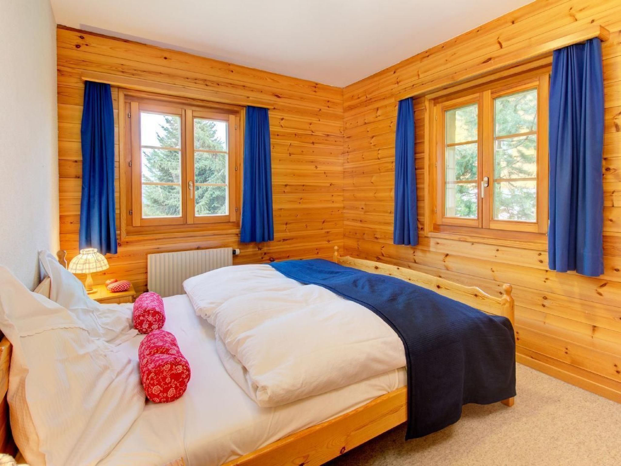 Une chambre dans une cabane en bois, avec deux lits, une fenêtre et une lampe.
