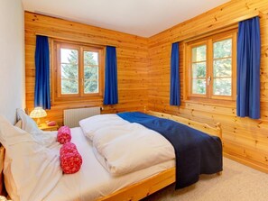 Ein Schlafzimmer einer Holzhütte mit zwei Betten, einem Fenster und einer Lampe.