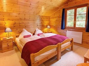 A wooden cabin bedroom with a bed, bedside tables, lamps, and a window. - Chalet Altitude 1900 by Interhome (Thyon-Les Collons)