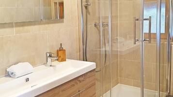 Une salle de bain moderne avec une douche à parois de verre, un meuble-lavabo en bois et un grand miroir.
