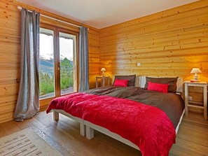 A wooden cabin bedroom with a bed, two bedside tables, and a window with curtains. - Chalet Bryher by Interhome (Thyon-Les Collons)