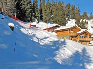 A snow-covered ski slope with a wooden lodge and a red safety net. - Chalet Bryher by Interhome (Thyon-Les Collons)
