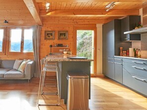 Eine moderne Küche mit Holzbalken, einer Bar und Blick ins Freie.