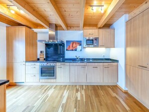 Eine moderne Küche mit Holzausstattung, einem Edelstahlbackofen, einer Mikrowelle und einem großen schwarzen Herd.