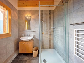 Ein modernes Badezimmer mit einer Duschkabine aus Glas, einem Holzbadezimmer-Möbel mit zwei Waschbecken und einer weißen Badewanne.