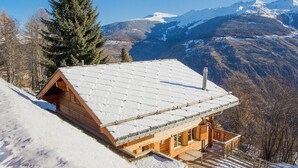 A wooden chalet with a sloped roof, surrounded by snow-covered mountains and a clear sky. - Chalet Greppon Blanc by Interhome (Hérémence)