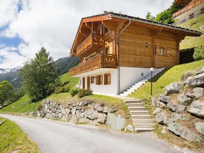 A wooden chalet with a balcony, stone steps, and a mountain backdrop. - Chalet Mountain Star by Interhome (Hérémence)