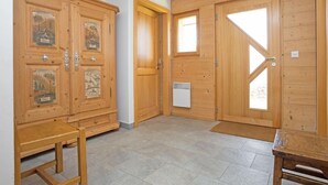 Una habitación con puertas de madera, una mesita, un banco y un radiador.