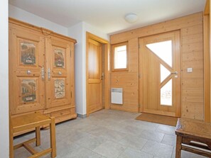 A room with wooden double doors, a small table, a bench, and a radiator. - Chalet Mountain Star by Interhome (Hérémence)