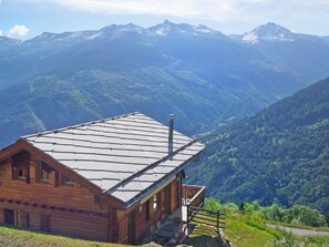A wooden cabin with a sloped roof, a balcony, and a view of a mountainous landscape. - Etoile des 4 Vallees by Interhome (Hérémence)