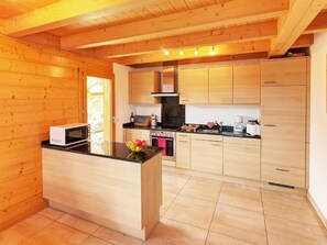 A wooden interior with a kitchen area featuring a central island, cabinets, and a stove. - Etoile des 4 Vallees by Interhome (Hérémence)
