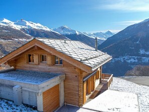 A wooden chalet with a sloped roof, a concrete foundation, and a wooden deck. - Chalet Falcons Nest by Interhome (Hérémence)
