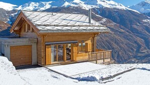 A wooden cabin with a balcony, a garage, and a view of snow-covered mountains. - Chalet Falcons Nest by Interhome (Hérémence)