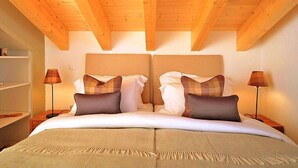 A double bed with a headboard, two bedside tables, and two lamps. - Chalet Falcons Nest by Interhome (Hérémence)