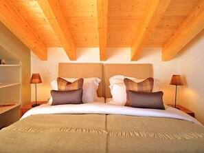 A double bed with a headboard, two bedside tables, and two lamps. - Chalet Falcons Nest by Interhome (Hérémence)