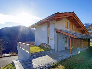 A two-story chalet with a balcony, stone steps, and a view of mountains. - Chalet Ourson Blanc by Interhome (Hérémence)