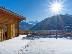 Een houten gebouw met een balkon met uitzicht op een besneeuwd berglandschap.