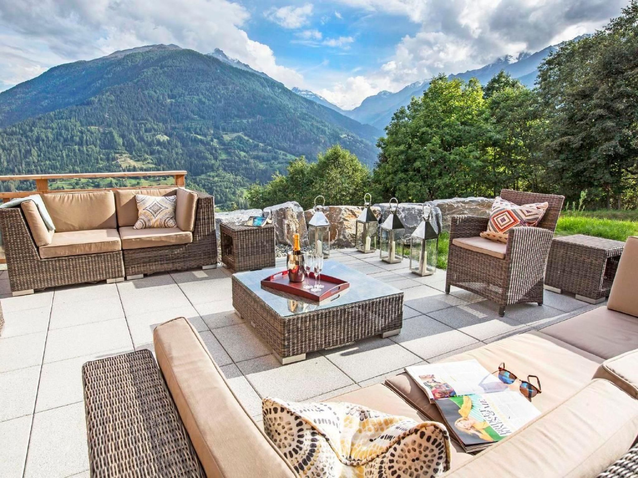 An outdoor seating area with wicker furniture and a view of mountains.