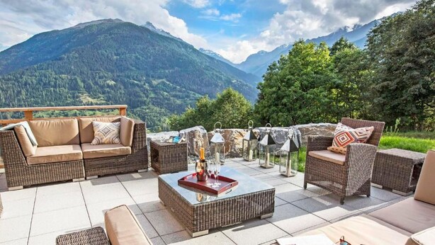 An outdoor seating area with wicker furniture and a view of mountains. - Chalet des Etoiles by Interhome (Hérémence)
