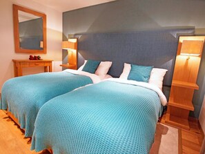 Ein Doppelzimmer mit zwei Betten, einem Nachttisch, einem Spiegel und Nachttischlampen.