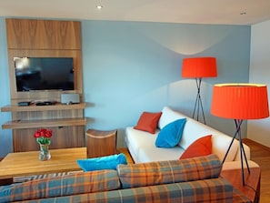 A modern living room with a flat-screen TV, a sofa with plaid cushions, a coffee table with a vase of flowers, and a floor lamp. - Ski Heaven Veysonnaz by Interhome (Veysonnaz)