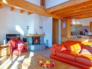 Ein gemütliches Wohnzimmer mit Kamin, einer roten Ledersofa, einem Fernseher und einem Esstisch mit Obst.