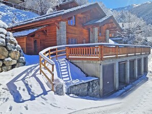 Eine Holzhütte mit steinernen Fundamenten, einer Holzterrasse und einer Steinwand.
